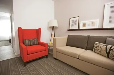 a living room with a couch and a red chair at Country Inn & Suites by Radisson, Cincinnati Airport, KY in Hebron