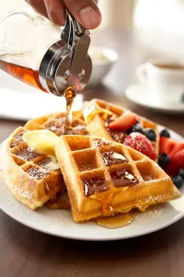 a person is pouring syrup onto a plate of waffles at Country Inn & Suites by Radisson, Cincinnati Airport, KY in Hebron