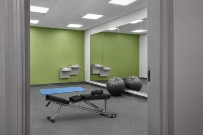 a room with a gym with a bench and mirrors at Spark by Hilton Washington Meadowlands Blvd in Washington