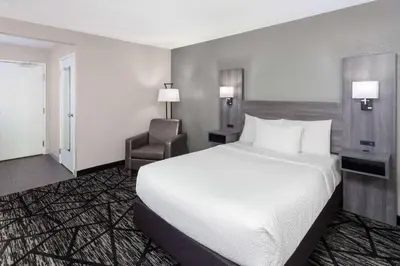 a hotel room with a bed and a chair at La Quinta Inn by Wyndham Cleveland Independence in Independence