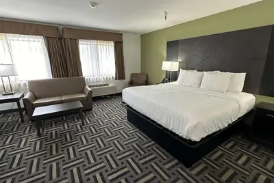 a hotel room with a large bed and a chair at La Quinta Inn and Suites by Wyndham Cincinnati North in Springdale