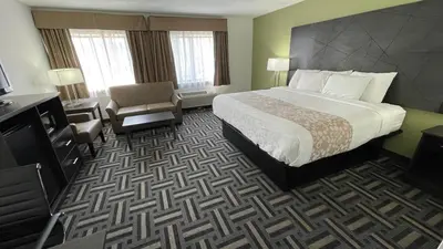 a hotel room with a bed and a chair at La Quinta Inn and Suites by Wyndham Cincinnati North in Springdale