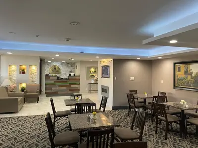 a restaurant with tables and chairs and a living room at La Quinta Inn and Suites by Wyndham Cincinnati North in Springdale