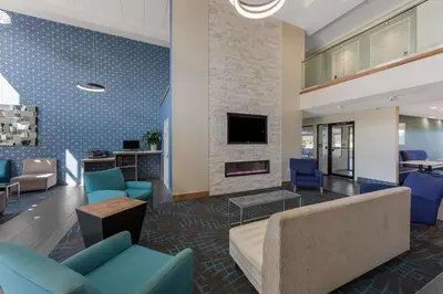 a lobby with blue chairs and a fireplace at Comfort Inn & Suites Tipp City Dayton North I-75 in Tipp City