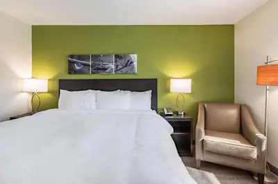 a hotel room with a bed and a chair at Sleep Inn & Suites Mt Hope near Auction & Event Center in Millersburg