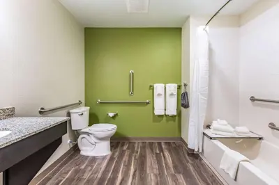 a bathroom with a toilet and a green wall at Sleep Inn & Suites Mt Hope near Auction & Event Center in Millersburg