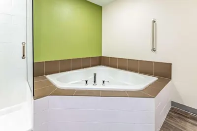 a bath tub in a bathroom with a green wall at Sleep Inn & Suites Mt Hope near Auction & Event Center in Millersburg