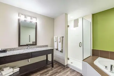 a bathroom with a sink and a mirror and a tub at Sleep Inn & Suites Mt Hope near Auction & Event Center in Millersburg