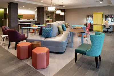 a living room with a couch and tables and chairs at Home2 Suites By Hilton New Albany Columbus in New Albany