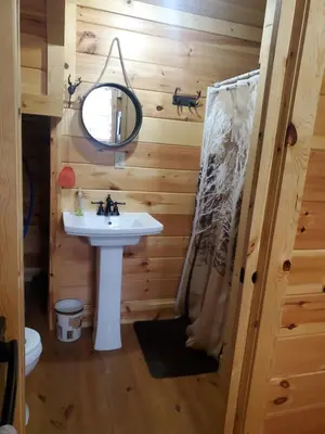 a bathroom with a sink and a mirror at The Hampton - An Amish Built Deluxe Log Cabin in Genoa