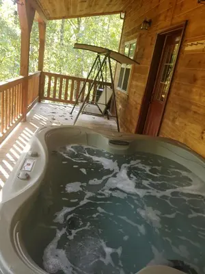 a jacuzzi tub on the deck of a cabin at The Genoa - An Amish Built Deluxe Cabin in Genoa