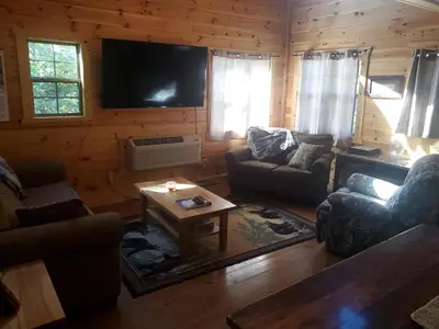 a living room with couches and a tv in a log cabin at The Genoa - An Amish Built Deluxe Cabin in Genoa