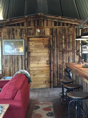 a living room with a red couch and a bar at The Highlander - Rustic Mountain Yurt in Genoa