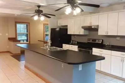 a kitchen with white cabinets and a black counter top at The Bunkhouse - 3 BR, 2 BA Deluxe Cabin in Genoa