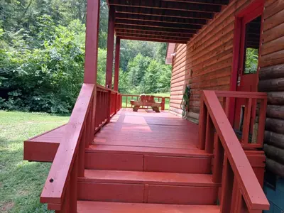 a porch of a log cabin with a red deck at The Bunkhouse - 3 BR, 2 BA Deluxe Cabin in Genoa