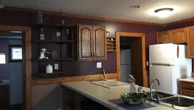 a kitchen with wooden cabinets and a white refrigerator at The Lodge - Chestnut Log Cabin in Genoa