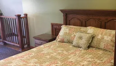 a bedroom with a bed with a wooden head board at The Lodge - Chestnut Log Cabin in Genoa