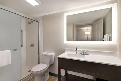 a bathroom with a toilet and a sink and a mirror at La Quinta Inn by Wyndham Columbus Airport Area in Columbus