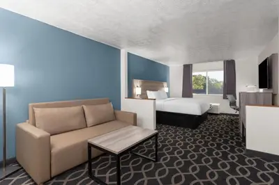 a hotel room with a couch and a bed at Baymont by Wyndham Piqua in Piqua