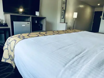 a large bed with a white blanket on top of it at Baymont by Wyndham Piqua in Piqua