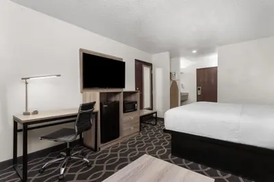 a hotel room with a bed and a desk with a television at Baymont by Wyndham Piqua in Piqua