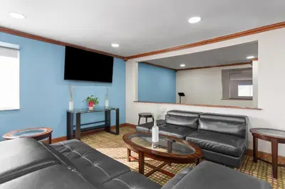 a living room with black leather furniture and a flat screen tv at Baymont by Wyndham Piqua in Piqua