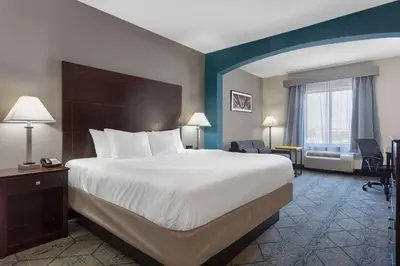 a hotel room with a large bed and a chair at La Quinta by Wyndham Columbus West - Hilliard in Columbus