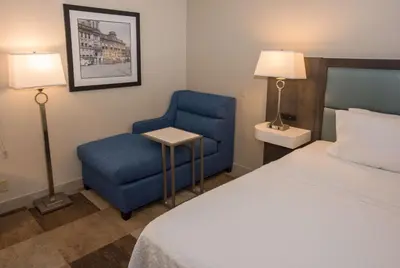 a hotel room with a bed and a blue chair at Hampton Inn Wooster in Wooster