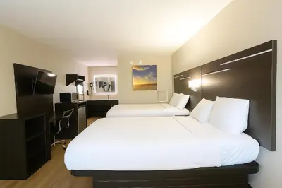 a hotel room with two beds and a television at Paragon Inn Hillsboro in Hillsboro