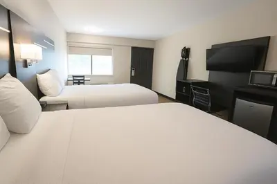 a hotel room with two beds and a flat screen tv at Paragon Inn Hillsboro in Hillsboro