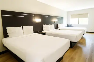 two beds in a hotel room with white sheets at Paragon Inn Hillsboro in Hillsboro