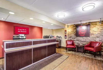 a lobby with a bar and two red chairs at Red Roof Inn Lexington in Lexington