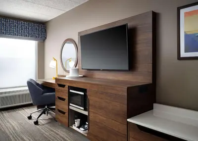 a room with a tv and a desk with a chair at Hampton Inn Troy in Troy