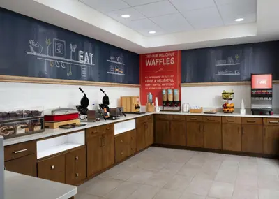 a large kitchen with wooden cabinets in a restaurant at Hampton Inn Troy in Troy