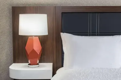a lamp on a night stand next to a bed at Hampton Inn & Suites Fort Wayne Downtown in Fort Wayne