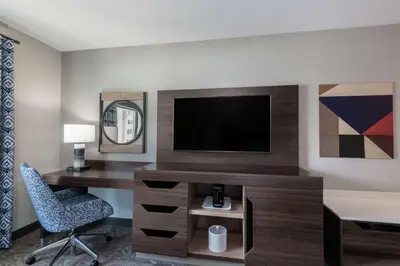 a room with a desk and a television and a chair at Hampton Inn & Suites Fort Wayne Downtown in Fort Wayne