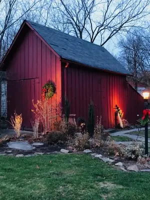 a red barn with a black roof in a yard at Riverside Gables Bed and Breakfast in Berea