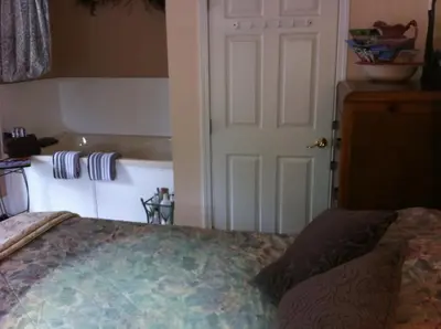 a bedroom with a bed and a door and a tub at Emerald Necklace Inn Bed and Breakfast in Lakewood
