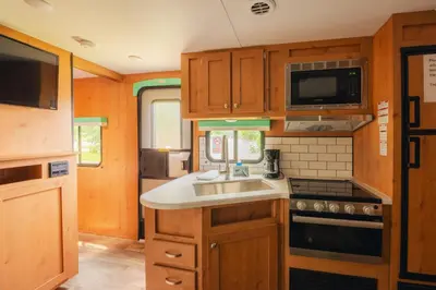 a kitchen with a sink and a stove and a microwave at Pine Creek Cabins & Camping Resort in South Bloomingville