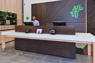 a man standing behind a desk with two laptops at Holiday Inn & Suites - Toledo Southwest - Perrysburg by IHG in Perrysburg