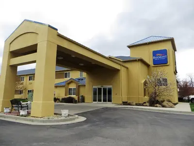 a large yellow building with a mobil gas station at Baymont by Wyndham Fort Wayne in Fort Wayne