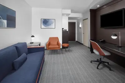 a hotel room with a blue couch and a desk at Courtyard Cleveland University Circle in Cleveland