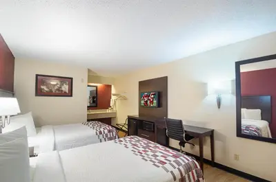 a hotel room with two beds and a desk and a mirror at Red Roof Inn Dayton - Fairborn/Nutter Center in Fairborn