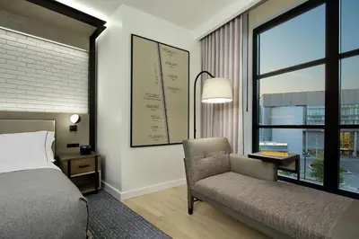 a bedroom with a bed and a chair and a window at Canopy By Hilton Columbus Downtown Short North in Columbus