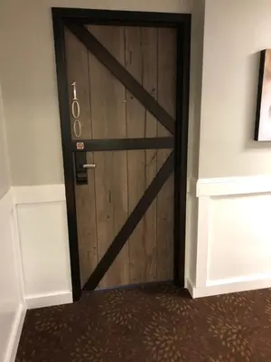 a wooden door with a metal handle in a room at Cedar Stables Inn & Suites in Sandusky