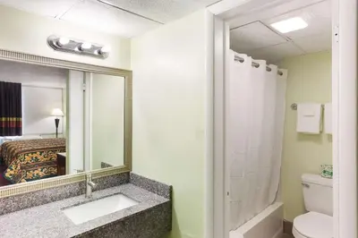 a bathroom with a sink and a toilet and a mirror at Rodeway Inn South Point in South Point