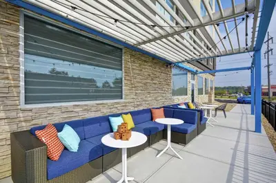 a patio with a blue couch and tables at Tru By Hilton Beavercreek Dayton in Fairborn