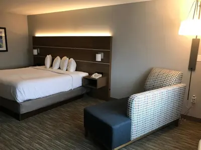 a hotel room with a bed and a chair at Holiday Inn Express - Toledo West - Napoleon by IHG in Napoleon