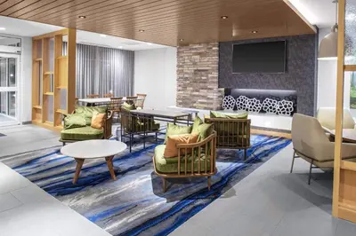 a lobby with chairs and a table and a tv at Fairfield Inn & Suites by Marriott Indianapolis Greenfield in Greenfield