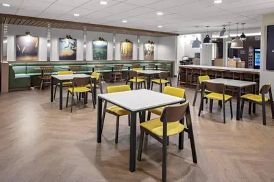 a restaurant with tables and yellow chairs and a counter at Fairfield Inn & Suites by Marriott Indianapolis Greenfield in Greenfield